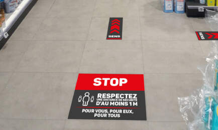 Stickers noir et rouge au sol pour avertir les patients qu'il faut respecter 1m de distance.