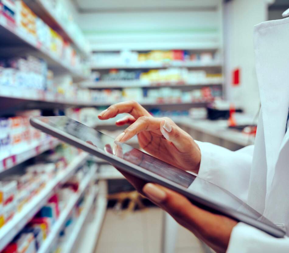 Pharmacienne en train de sélectionner des produits sur une tablette qu'elle tient dans sa main.