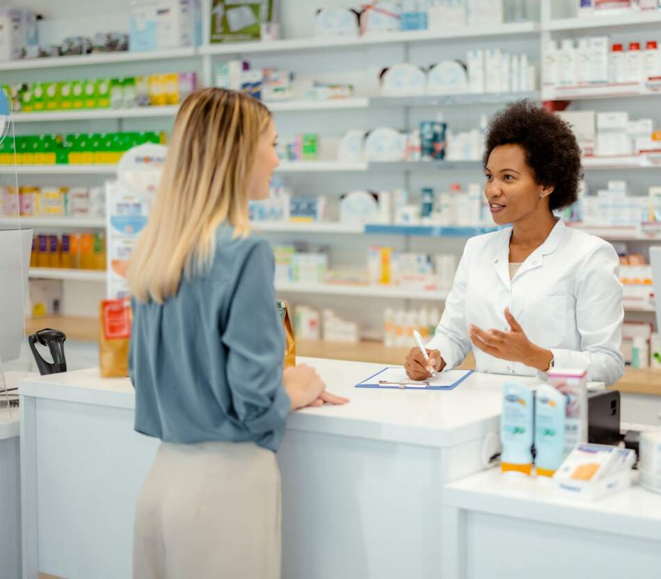 Une pharmacienne et un patient se tiennent au comptoir de la pharmacie