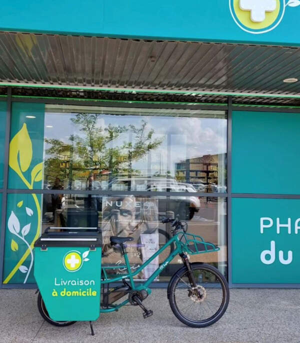 Un vélo cargo aménagé aux couleurs de la pharmacie prêt à assurer la livraison de médicaments